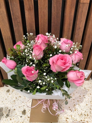 Bouquet of fresh pink roses and white baby's breath wrapped in white paper by Thornlie Flourist