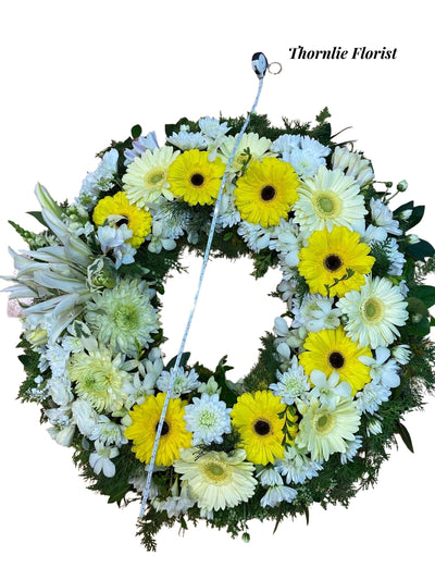 Funeral wreath with yellow gerbera daisies and white lilies by Thornlie Florist.