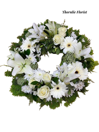 Pure Serenity Wreath with white lilies, roses, and gerberas by Thornlie Florist.