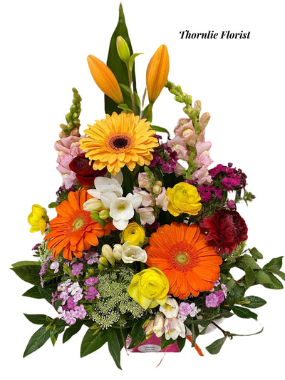Sunset Garden Box floral arrangement with orange gerberas, yellow roses, and pink snapdragons.