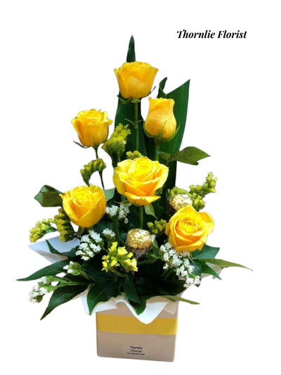 Golden Glow arrangement featuring bright yellow roses and white flowers in a gift box.