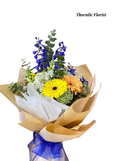 Elegant Bloom Bouquet with yellow gerbera, orange gerbera, and blue delphinium flowers.