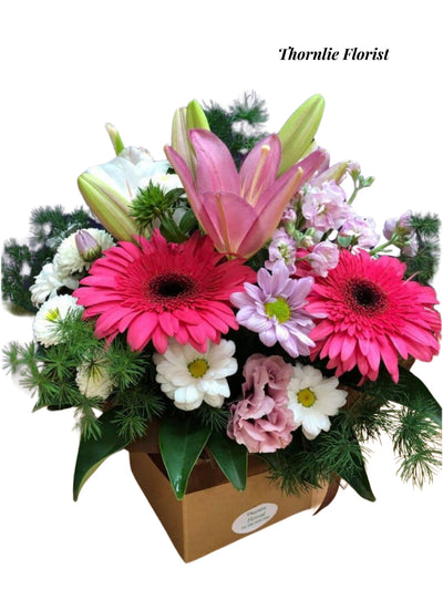 Lovely Melody flower arrangement with pink lilies, gerbera daisies, and white blossoms in a box.